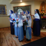 Sr. Mary Genevieve joins the sodalists at Mary Immaculate Queen parish in presenting May flowers to Our Lady Sister and sodalists at the City of Mary