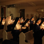 Holding their candles, lit from the Paschal candle flame, the Sisters follow along during the chanting of the Exultet at the Easter Vigil. Easter Vigil ceremonies in the convent cloister chapel