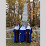 Sr. Mary Evangeline, Sr. Maria Dolorosa pose with Rev. Mother at the monument where Fr. Sebastian Rasle, missionary to the Abenaki Indians, was killed on August 23, 1724.