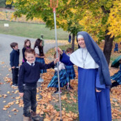 Sr. Mary Imelda works to get a ball out of the culvert with the help of a little boy and a long pole (Rathdrum, Idaho) Sister and students on a fall day