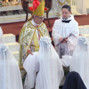 After having had their hair cut by the Bishop, our four postulants, in simple white dresses, receive their white novice veils.