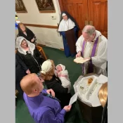 Sr. Bernardine Marie looks on while Father Francisco Radecki baptizes a tiny new parishioner of St. Joseph’s Church inWayne, Michigan.