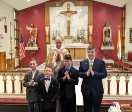 The pastor at Sacred Heart, Fr. Gregory Drahman, poses with four happy First Communicants.